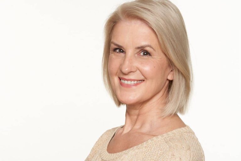 Smiling middle-aged woman with smooth skin, representing successful facelift recovery results.