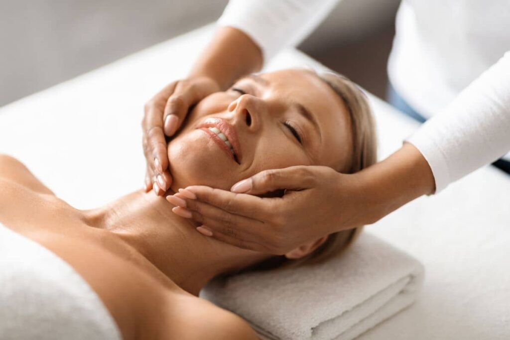 Woman receiving gentle facial massage, promoting long-lasting youthful appearance.