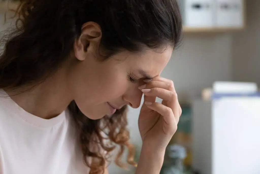 Woman holding her nose bridge in discomfort from breathing issues caused by a deviated septum