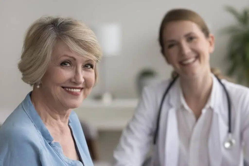 Happy older woman with doctor after rhinoplasty consultation to meet insurance documentation requirements
