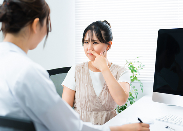 Woman discussing nasal concerns with plastic surgeon during detailed rhinoplasty consultation in medical office