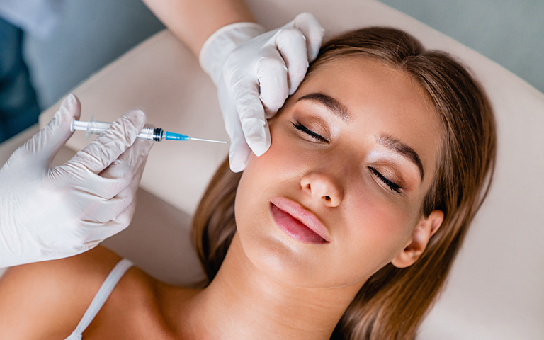 Woman receiving Botox injection near eye area with fine needle during in-office procedure designed for comfort and precision