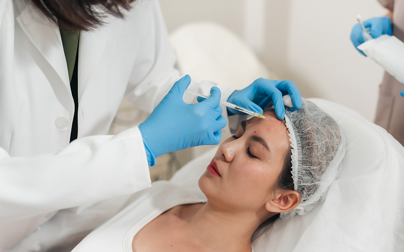 Woman receiving precise Botox injection in forehead area using fine needle technique to reduce muscle activity and wrinkles