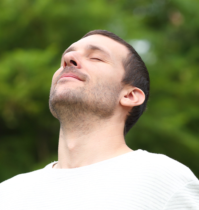 Man breathing deeply outdoors, symbolizing improved airflow and sinus relief after functional rhinoplasty surgery
