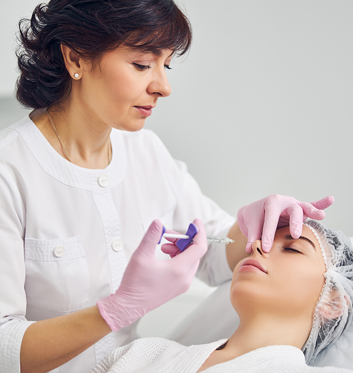 Doctor performing liquid rhinoplasty on patient using dermal filler injection for non-surgical nose enhancement.