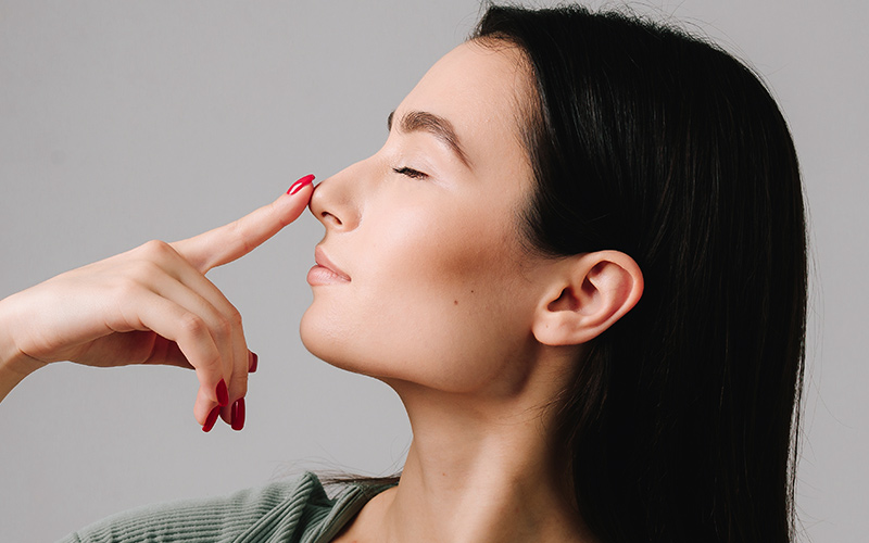 Woman gently pressing her nose, symbolizing nasal valve collapse and the need for functional rhinoplasty support