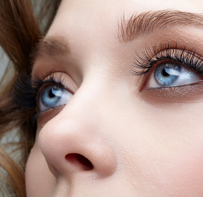 Close-up image of a woman's face, showing her eyes and the side of her nose, emphasizing the delicate features and the symmetry of her profile