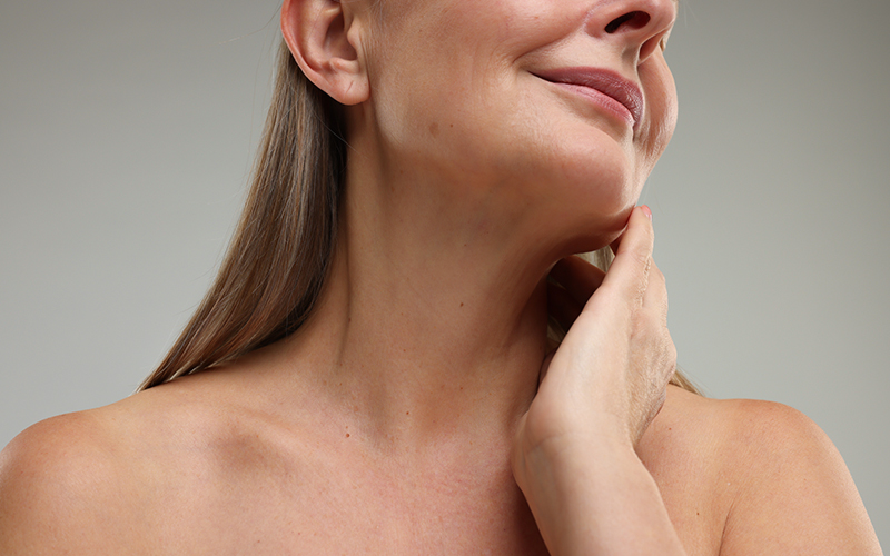 Close-up of mature woman gently touching her neck, showcasing natural Botox results without overcorrection or stiffness.