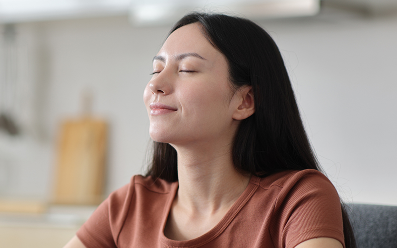 A woman sitting peacefully with her eyes closed, reflecting the relaxed, comfortable breathing that can be achieved through functional rhinoplasty.