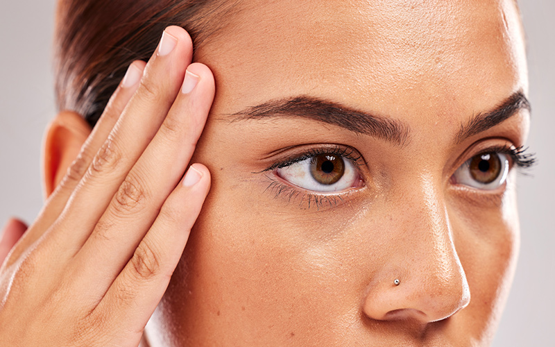 Woman gently touching temple with smooth skin, highlighting natural Botox results in Philadelphia by expert injectors.
