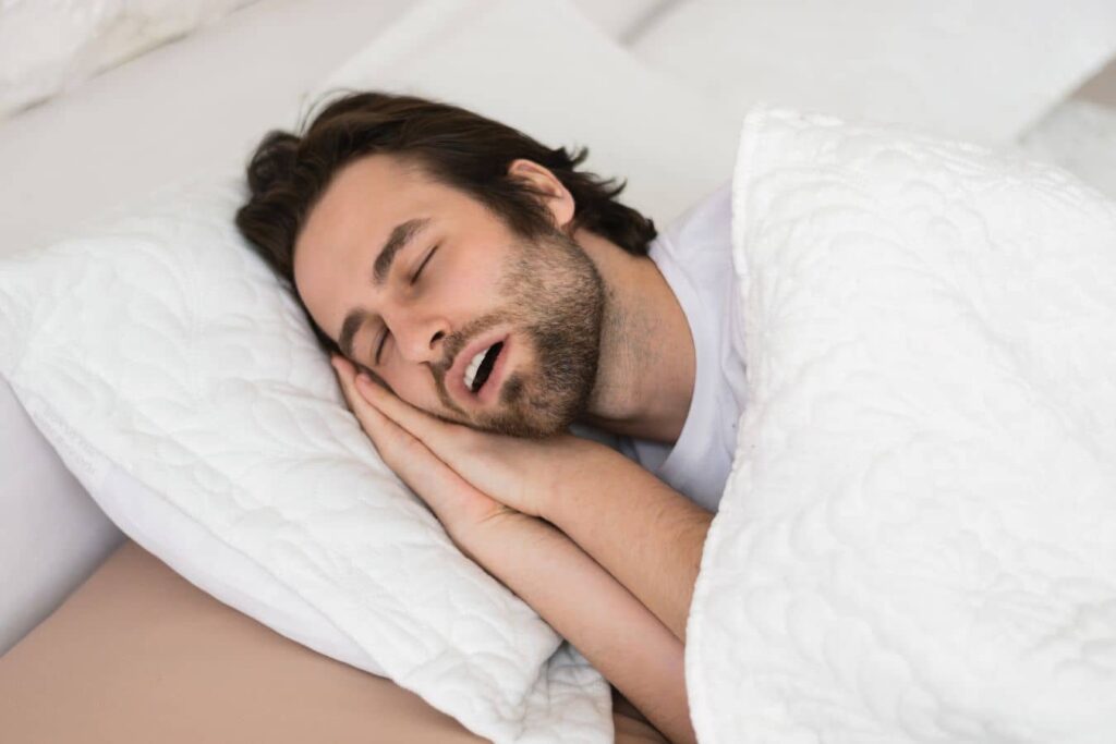 Man sleeping with open mouth, illustrating sleep apnea and reduced nasal airflow after rhinoplasty affecting sleep quality
