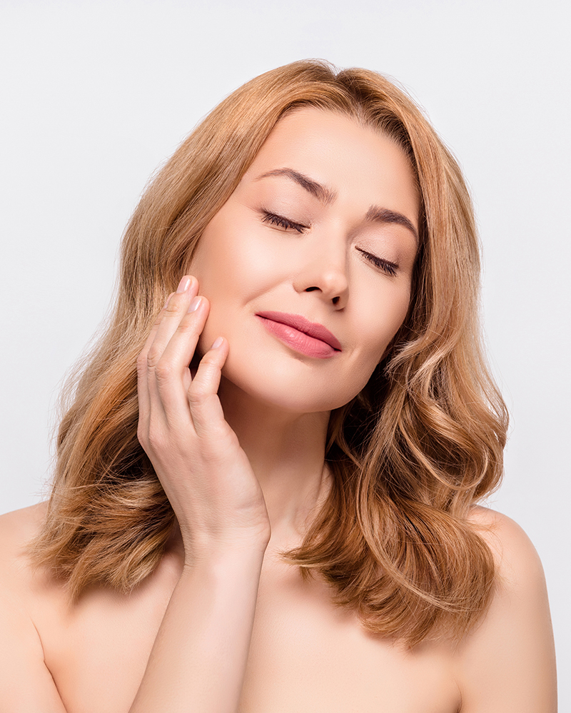 Relaxed woman touching her cheek, representing preparation and readiness for cheek and face liposuction treatment.