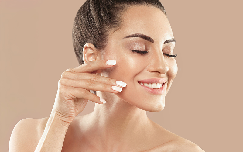 Woman with radiant skin touching her cheek, representing chemical peel results for smoother, even-toned complexion.