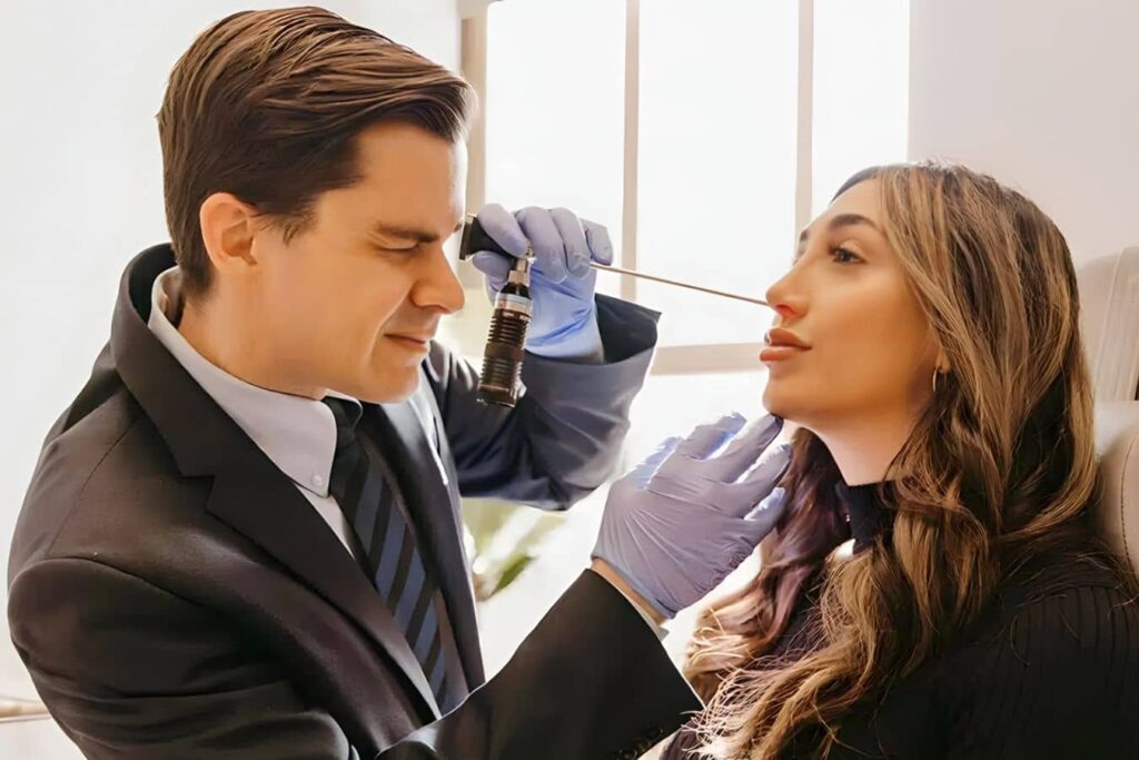 Surgeon examining patient’s nose in consultation, highlighting functional rhinoplasty expertise in Philadelphia, PA