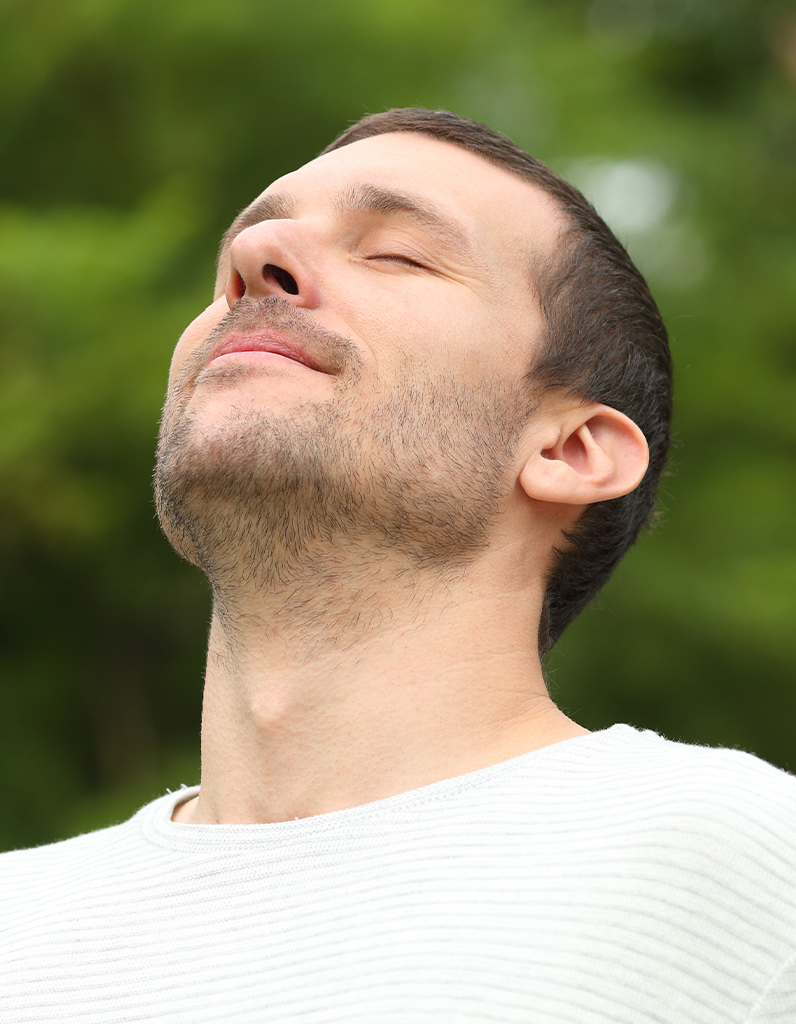 Man breathing deeply outdoors, symbolizing improved airflow and sinus relief after functional rhinoplasty surgery