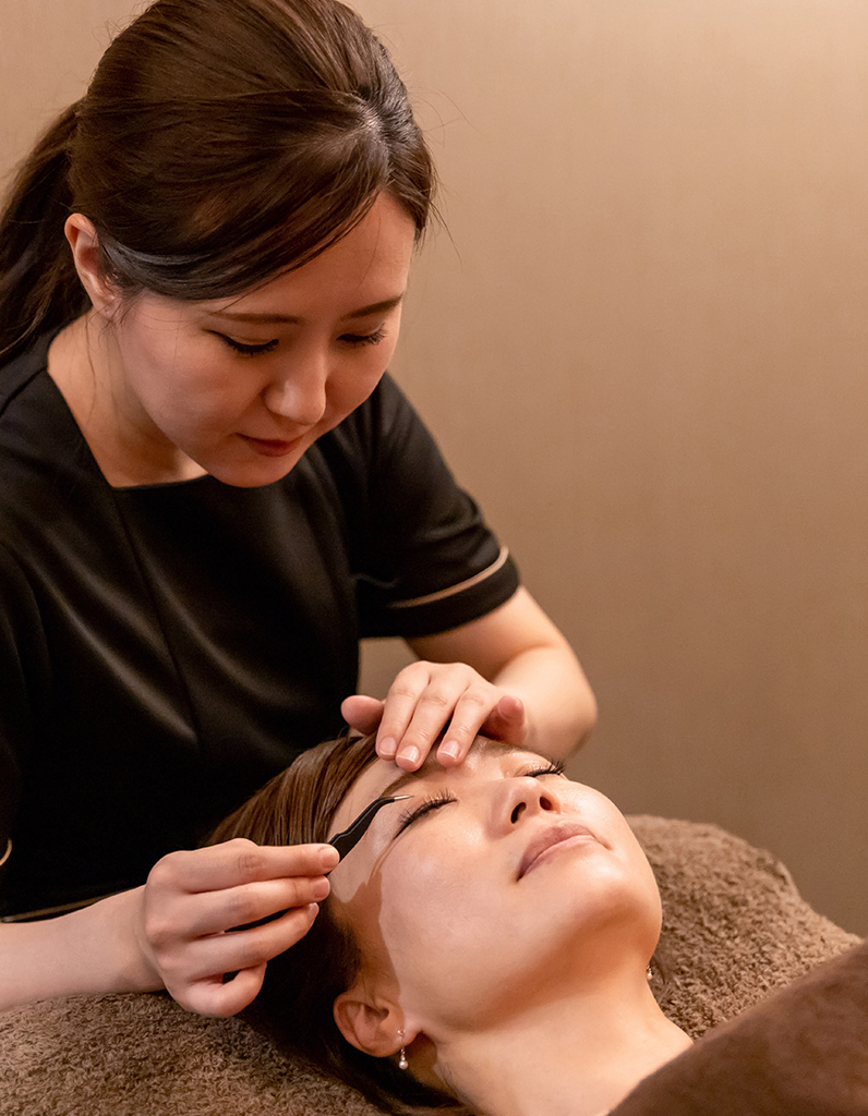 Aesthetician performing eyebrow treatment, representing professional lash and brow care.