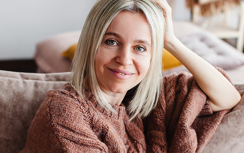 Smiling woman at home representing renewed confidence after reconstructive surgery in New Jersey and Philadelphia.