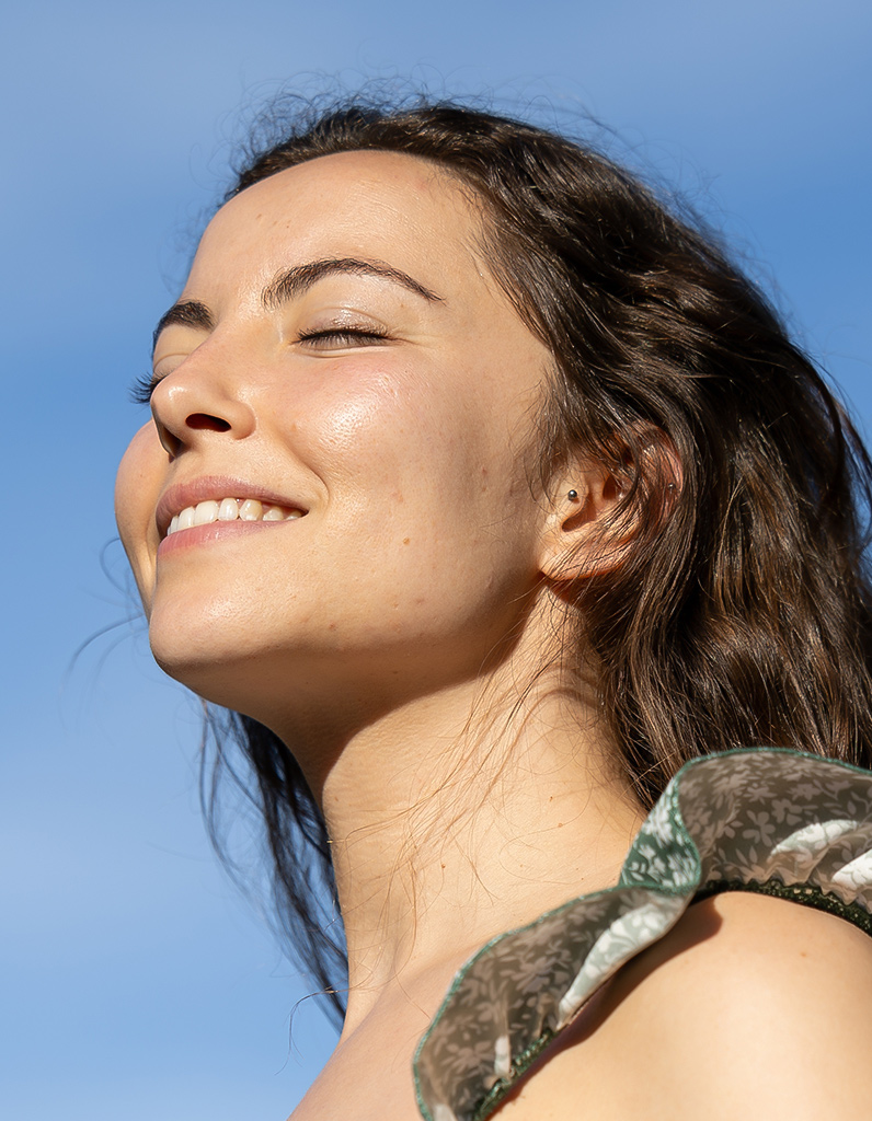 Smiling woman outdoors representing recovery period and healing after revision rhinoplasty surgery