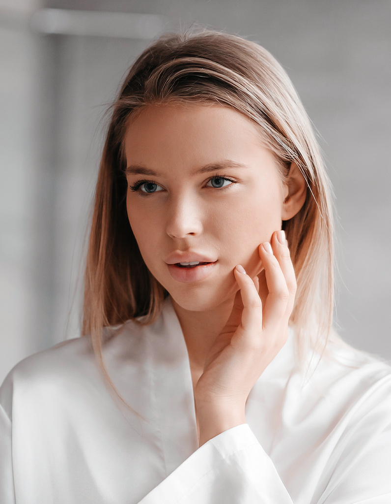 Woman touching face representing anatomical factors that can contribute to an overprojected nasal tip before rhinoplasty