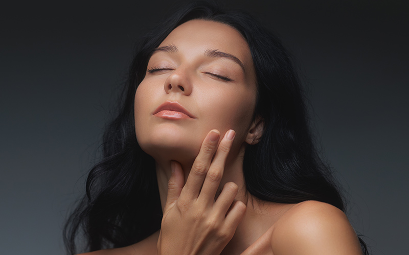 Woman gently touching nose and chin, illustrating facial harmony and nasal refinement relevant to rhinoplasty for wide nose.
