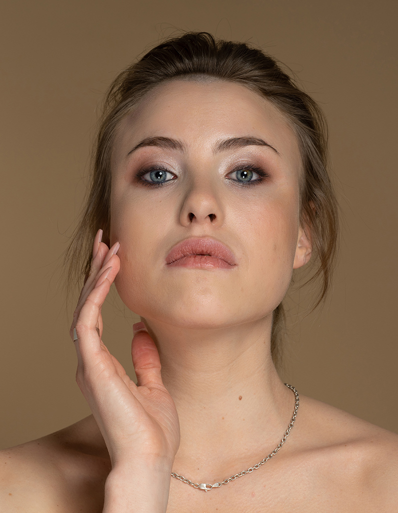 Front-facing woman highlighting nasal structure, illustrating concerns about wide nasal bridge, tip, and overall facial balance.