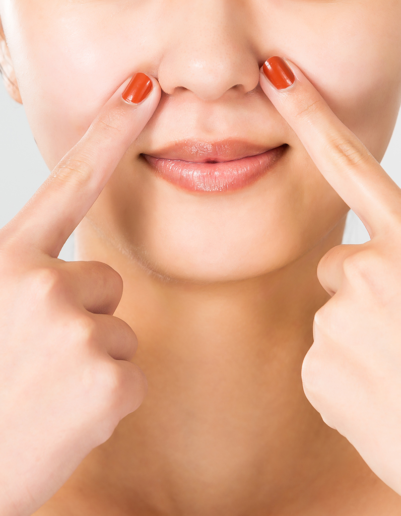 Person pointing to wide nostrils illustrating concerns about nostril width and nasal base proportion.