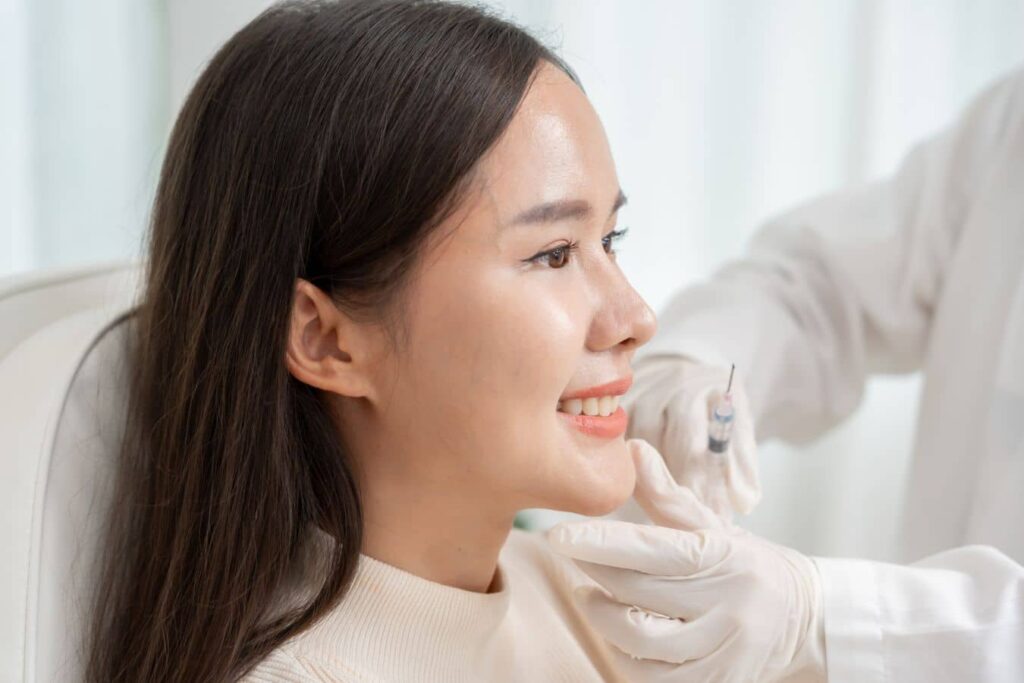 Specialist performing liquid rhinoplasty injection treatment to enhance nasal shape and facial symmetry.