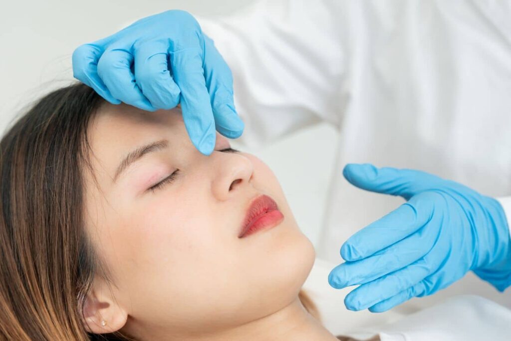 Doctor evaluating patient’s nose during rhinoplasty recovery to support healing and minimize scar appearance