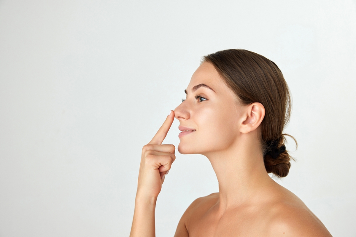 Woman touching nose beside rhinoplasty information for patients seeking cosmetic and functional nasal surgery in Sewell, NJ.